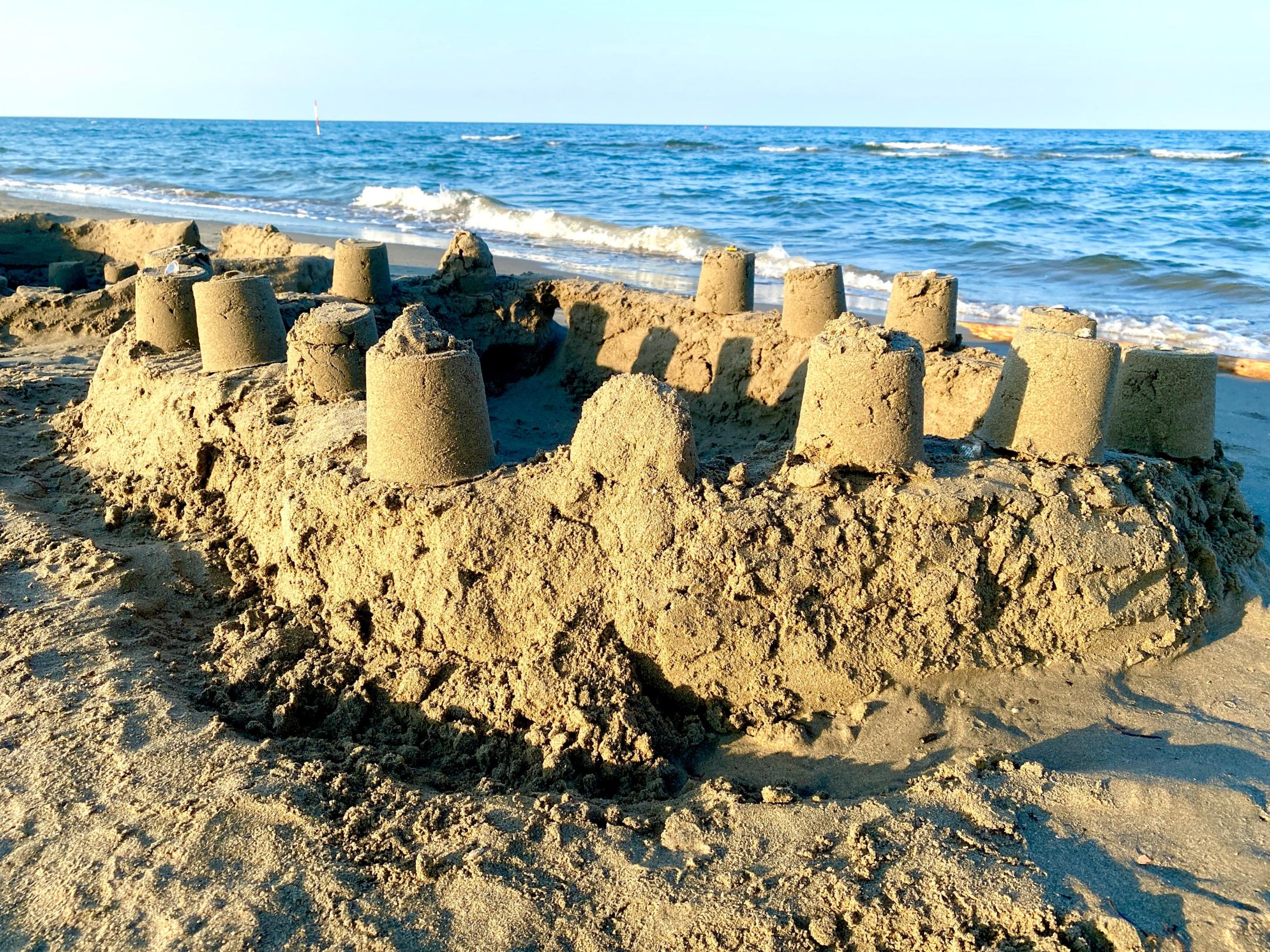Sandburgen am Meer. Das hellblaue Meer ist im Hintergrund.